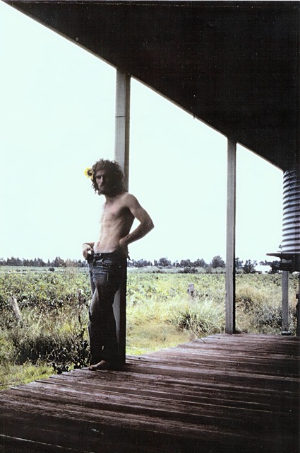 Walter Adamson at 23, standing on a farm veranda in the Sunraysia region in 1972, with flat irrigated farmland stretching to the horizon behind him.